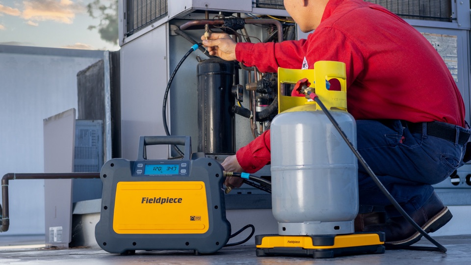 Fieldpiece HVAC technician using refrigerant tools at an outdoor unit